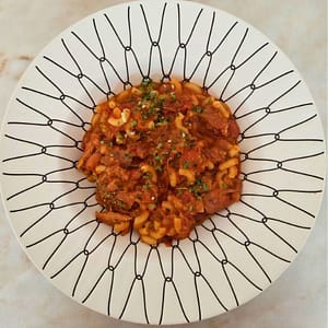Carne de porco estufada com massa cotovelos e feijão-manteiga.