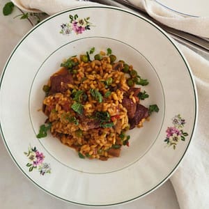 Prato de estufado de vitela com arroz e ervilhas num prato branca