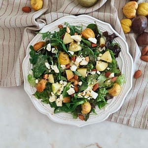 Salada saudável de Outono com folhas verdes, Feta, Maçã e Castanhas Assadas num prato branco