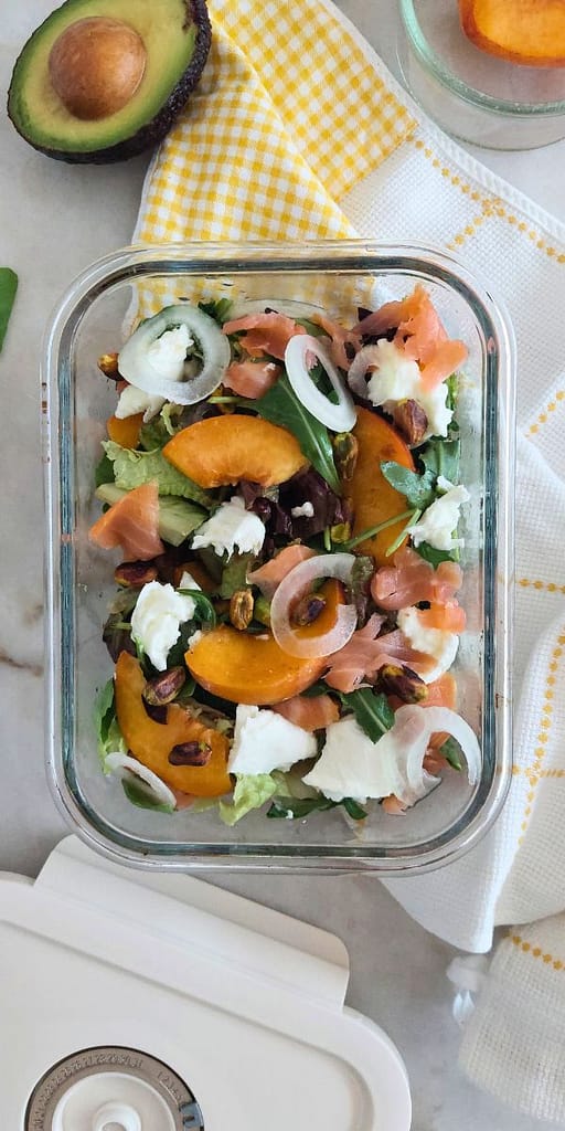 Salada colorida de pêssego, salmão e burrata com vinagrete e pistácios, servida como refeição leve e saudável para marmita