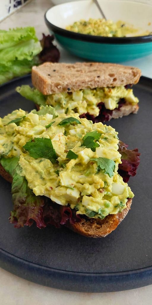 Close up de Salada de abacate com ovo cozido e ervas aromáticas numa fatia de pão torrado