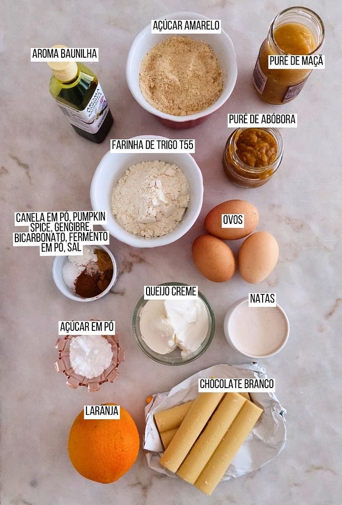 Ingredientes disposto na bancada laranja, queijo creme, ovos, chocolate branco, farinha, açucar