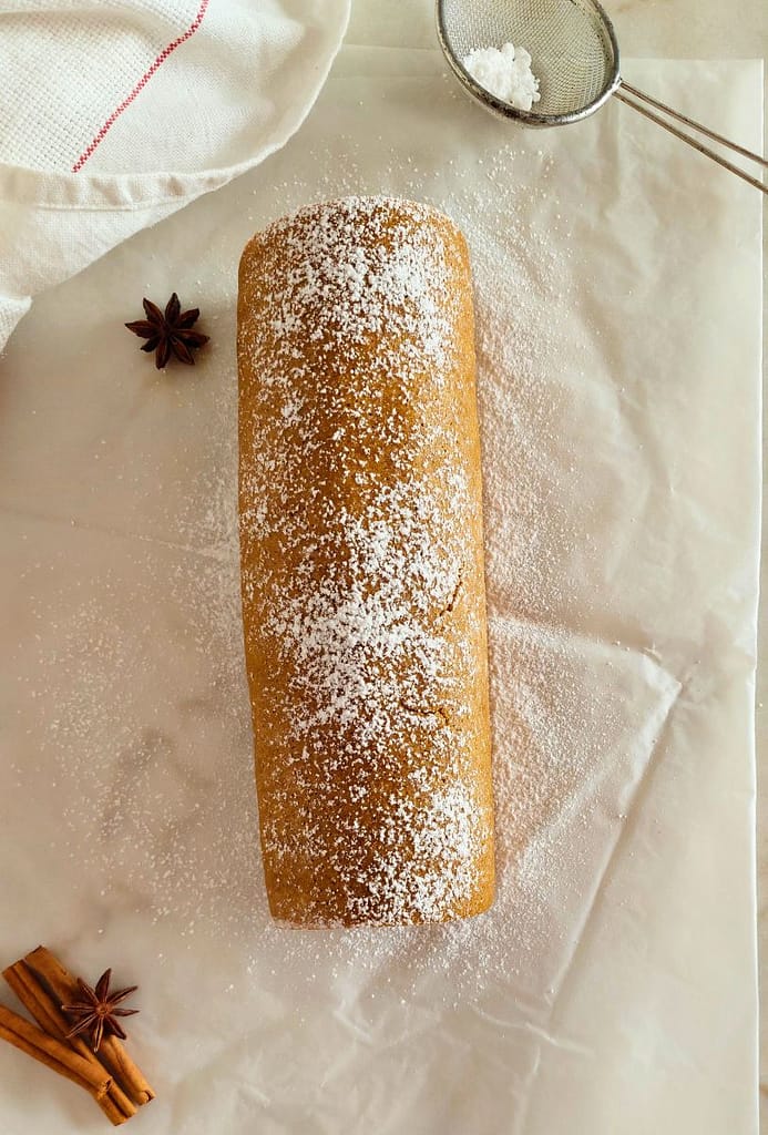 Torta de Abóbora com Recheio de Chocolate Branco enrolada sobre papel vegetal e plovilhada com açúcar