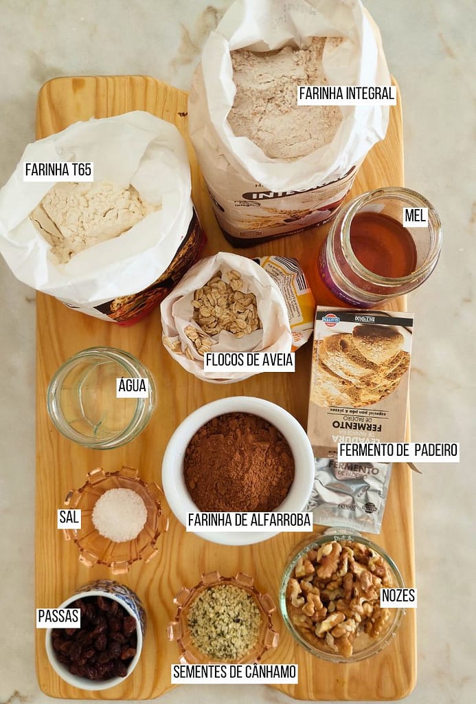 Ingredientes dispostos farinha, alfarroba, fermento, sal, passas e nozes