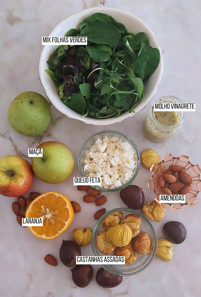 Ingredientes dispostos na bancada folhas verdes frescas, frutos secos e fruta