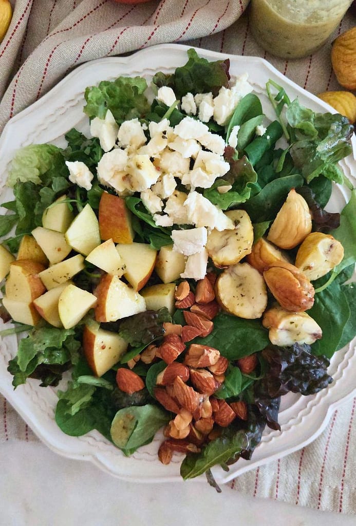 Salada de folhas verdes, Feta, Maçã e Castanhas Assadas num prato branco. Menu semanal 2026